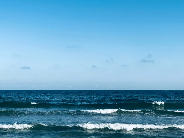 a surfer in black is riding a small wave