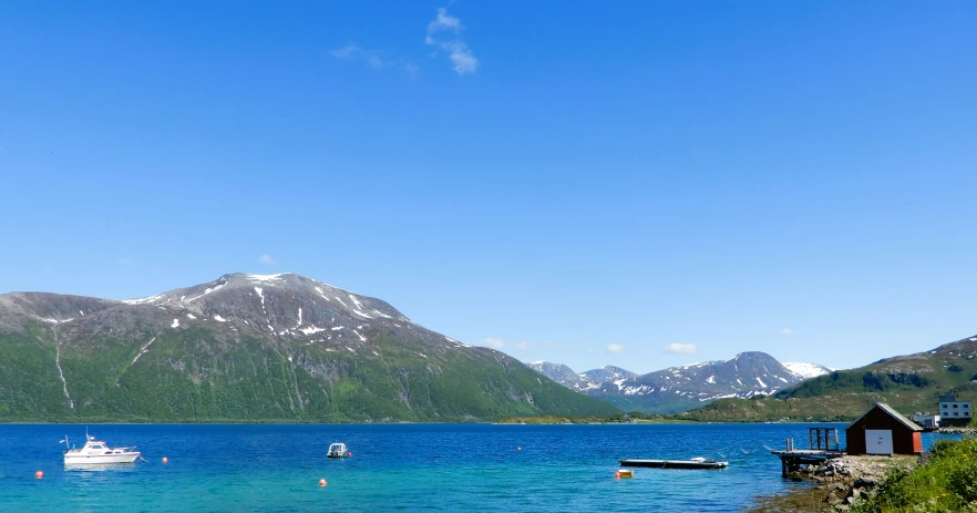 boats in the water near mountains and a house