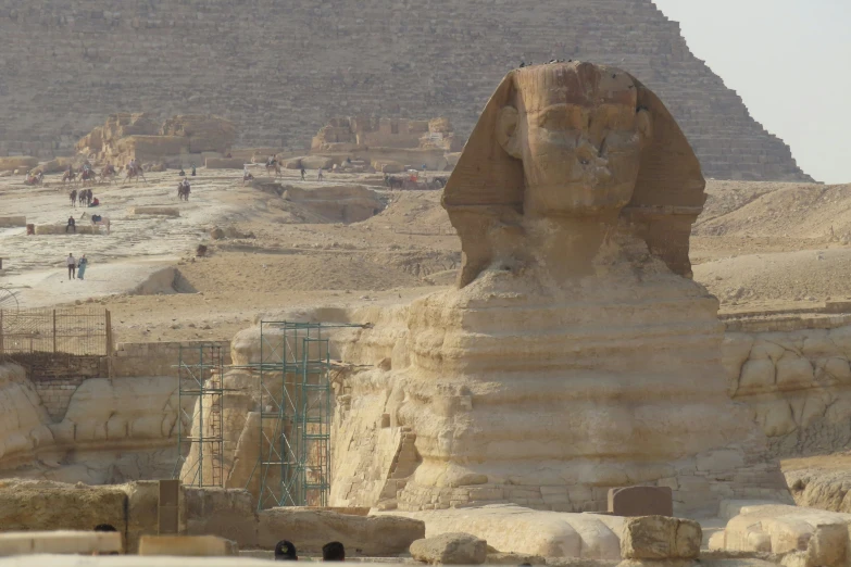 the sphinx stands near a statue in front of a pyramid