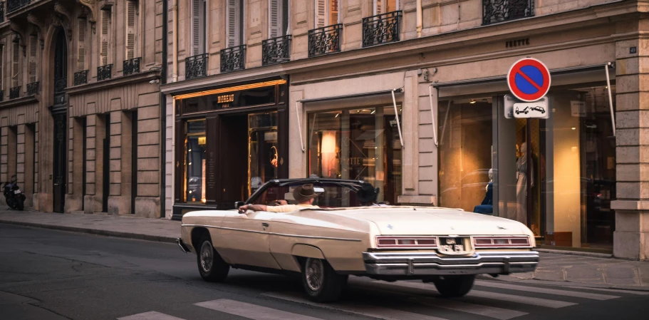 an old car parked in front of a tall building