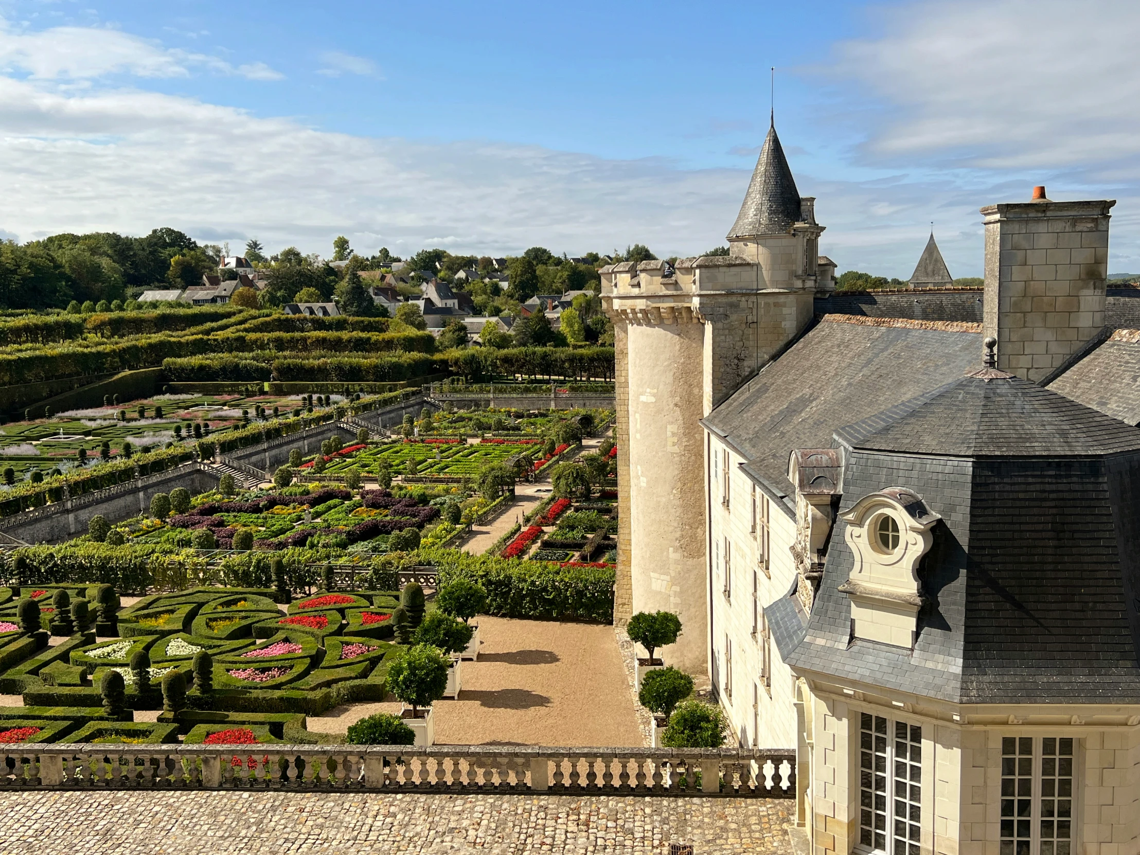 a castle like building with a formal garden lined driveway