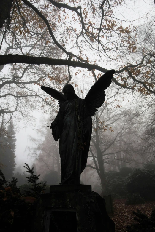 a statue is sitting in a foggy forest