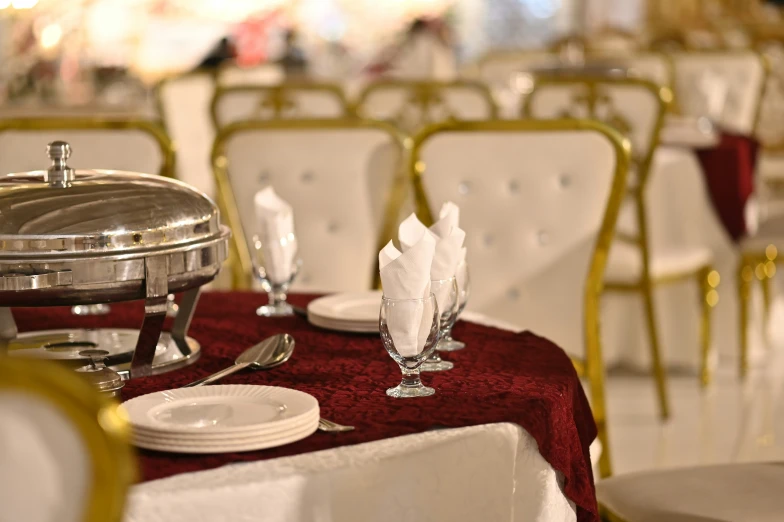 a buffet table set with silver ware, a server, and a red tablecloth