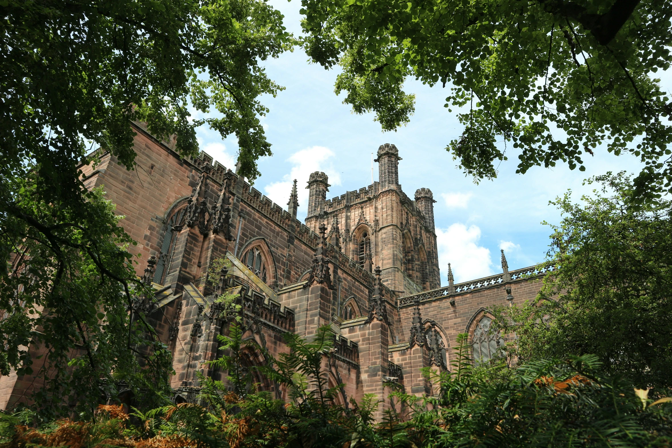 an old cathedral with a clock tower seen through the tree tops