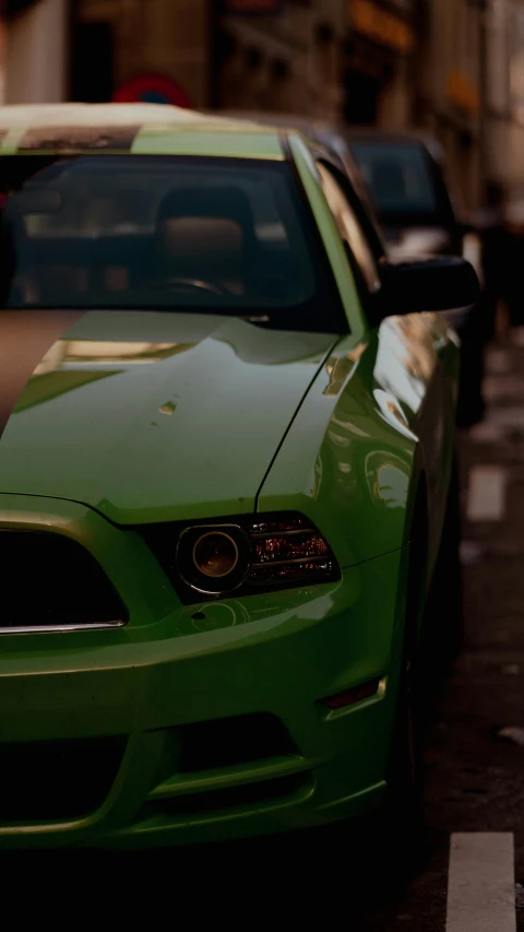 a green mustang parked on the side of a street