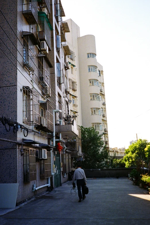 there is a man walking down the road near tall buildings