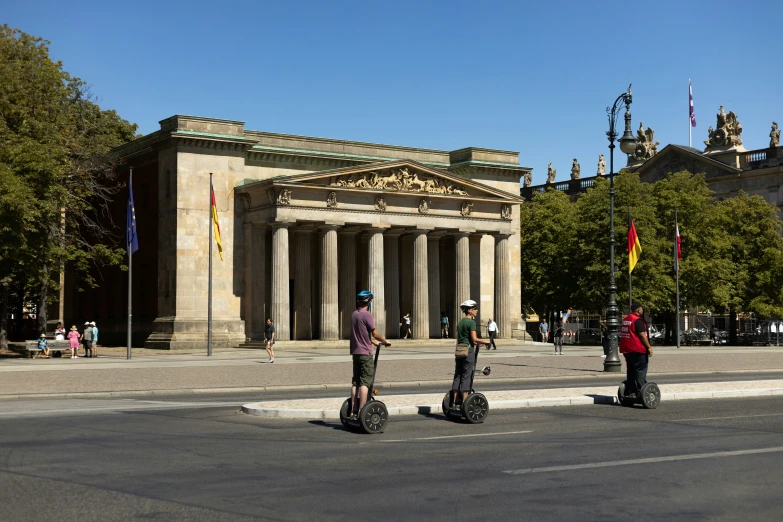 three people with scooters are standing in the middle of the street