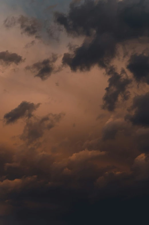 the sky with some clouds in it and dark orange hues