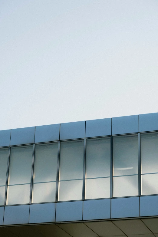 an airplane is flying near a building that has mirrored windows