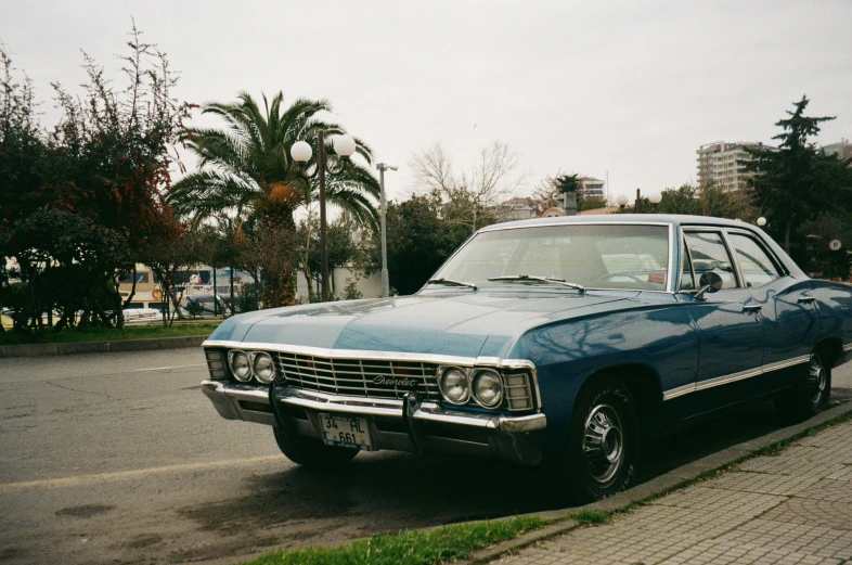 an old blue car is parked on the side of a road