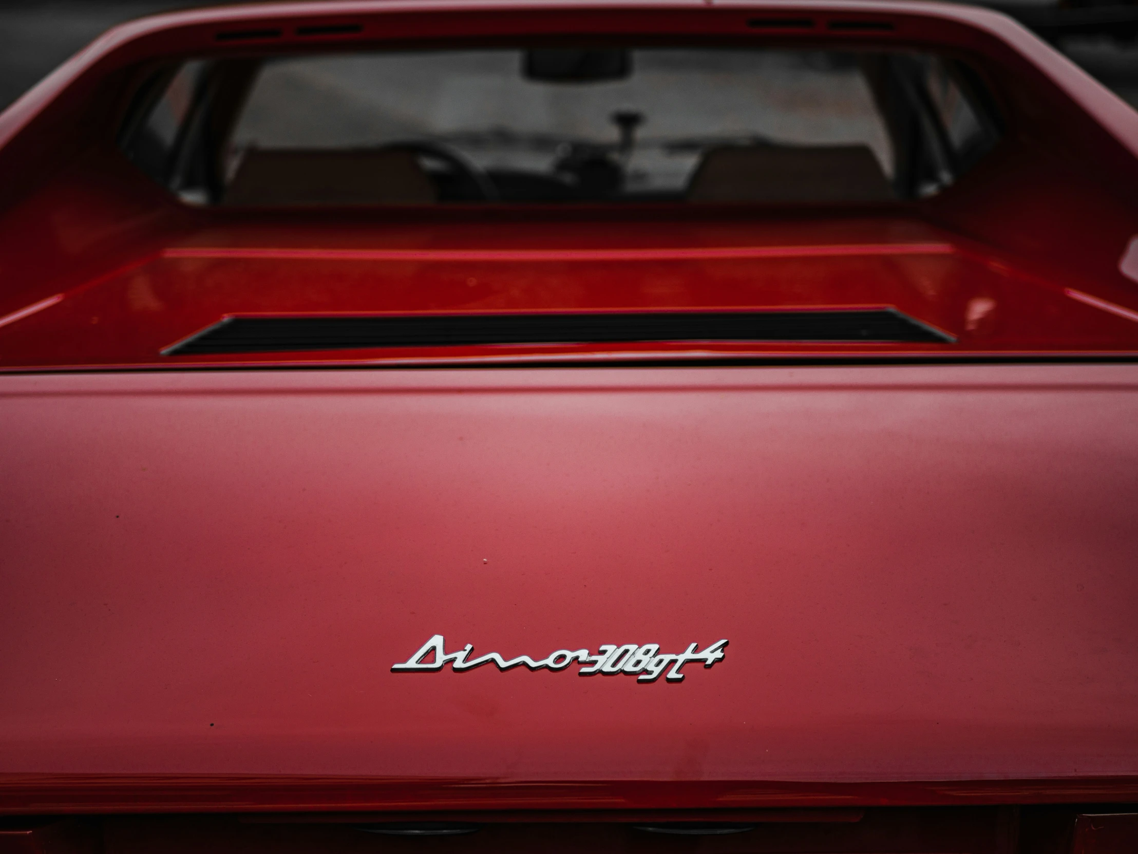 the front end of a red car with an emblem on it