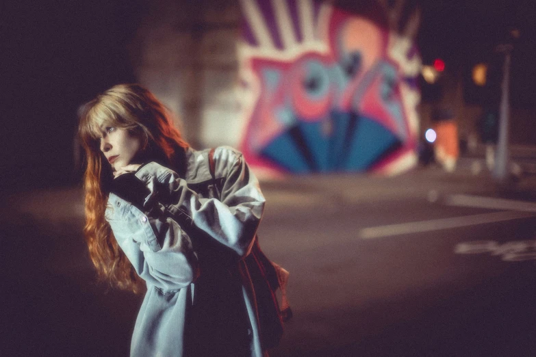 a girl standing on the side of a road holding onto her coat