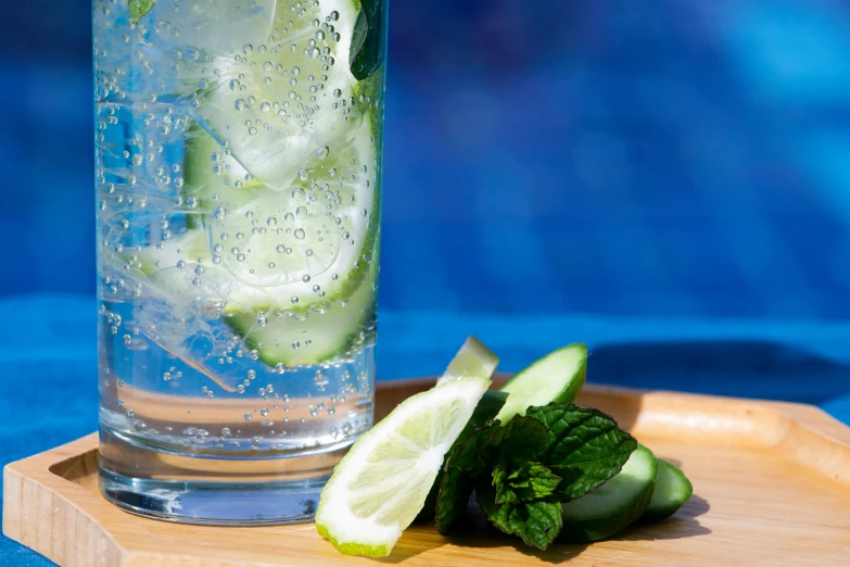 two cucumbers sit beside a glass with water