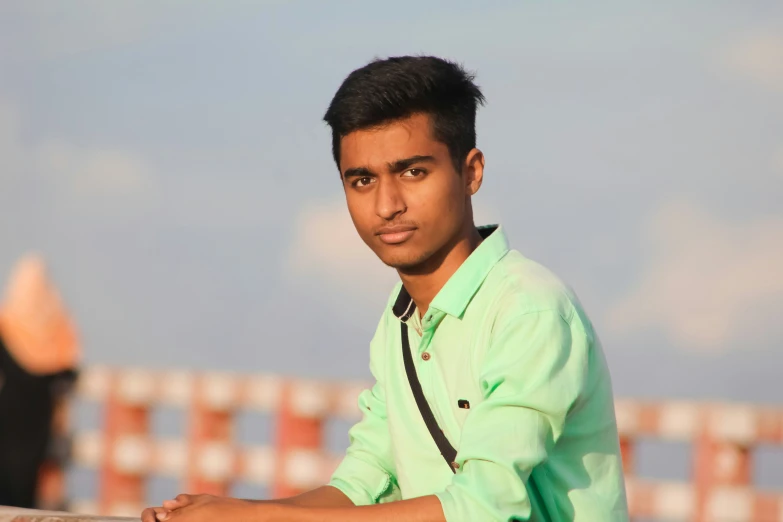 a young man poses next to a wooden fence