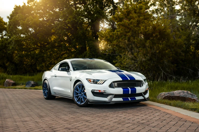 a white car with blue stripes parked on a brick road