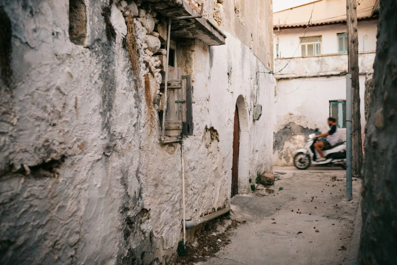 a person riding a motorcycle past a wall