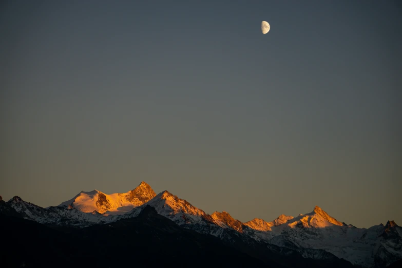 the moon is shining on top of some mountains