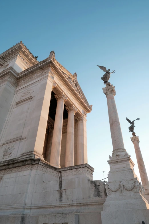 two tall white pillars with statues below them