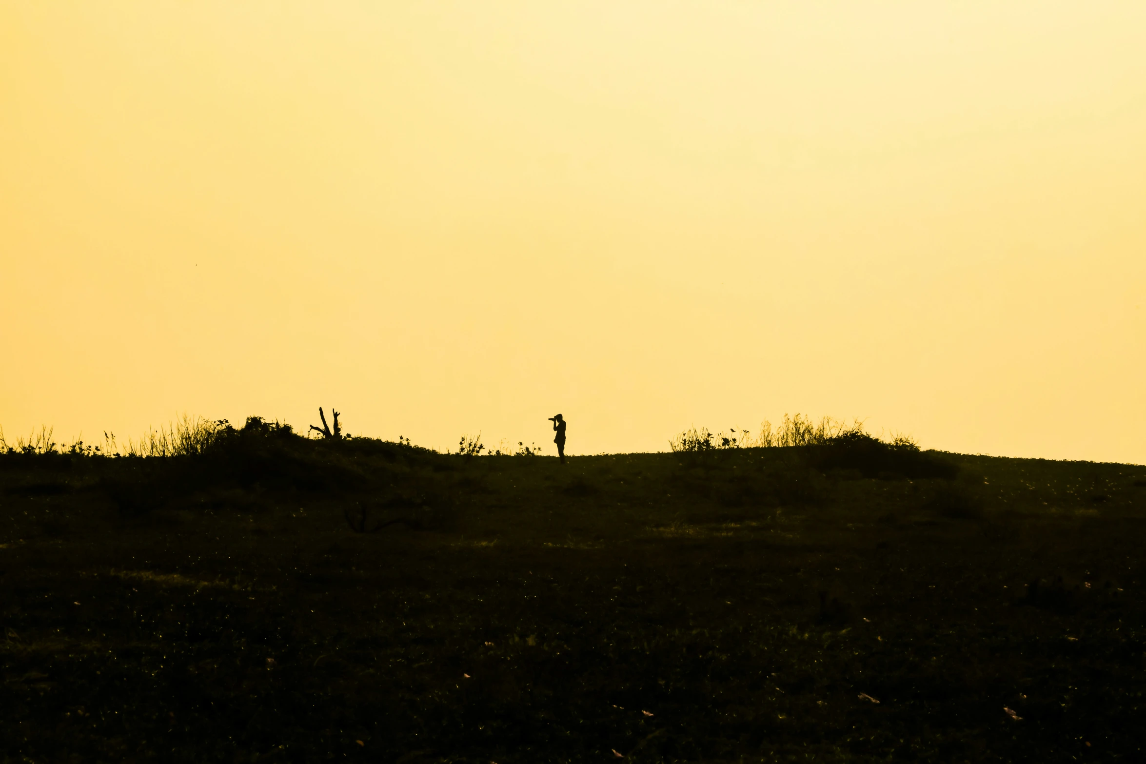 two people walking down a hill at sunset