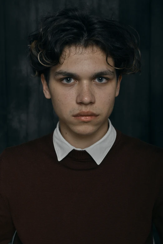 a young man with blue eyes and a red sweater