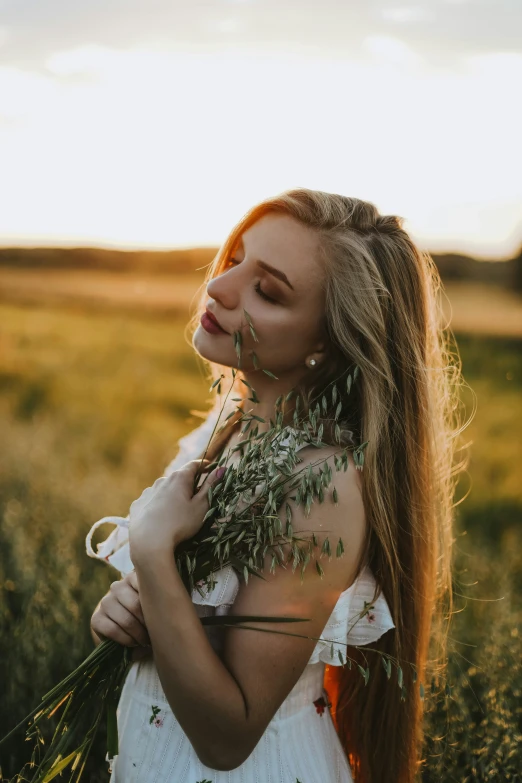 a woman standing in a field holding herbs