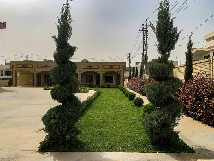 an outside courtyard with three green lawn bushes