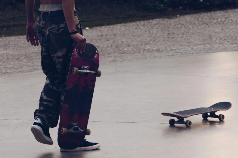 a person standing on the pavement next to a skateboard