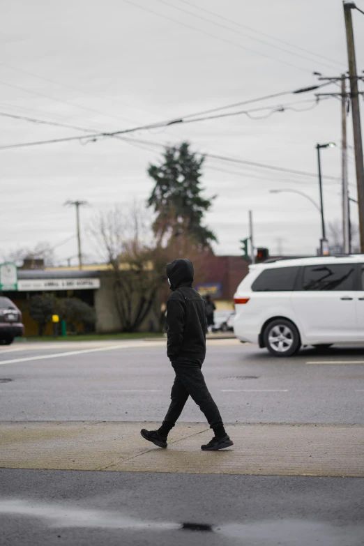 a young man walking down the street in a black hoodie