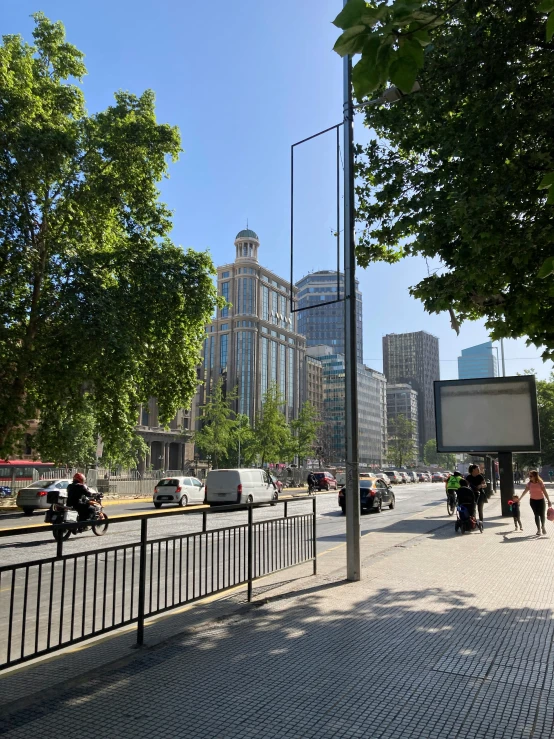 a public street with traffic and people walking near a fence