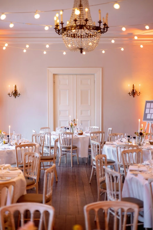 a dining room with white table cloths and white centerpieces