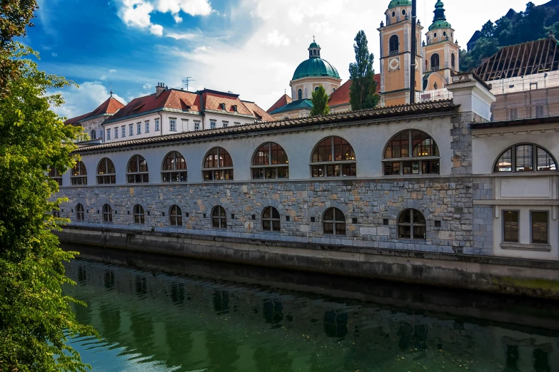 many windows are in a stone building beside a body of water