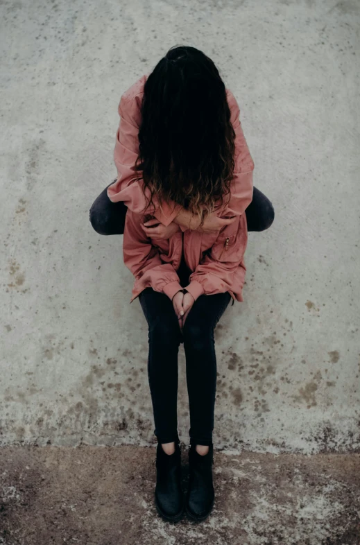 a little girl sitting on the ground in front of a wall