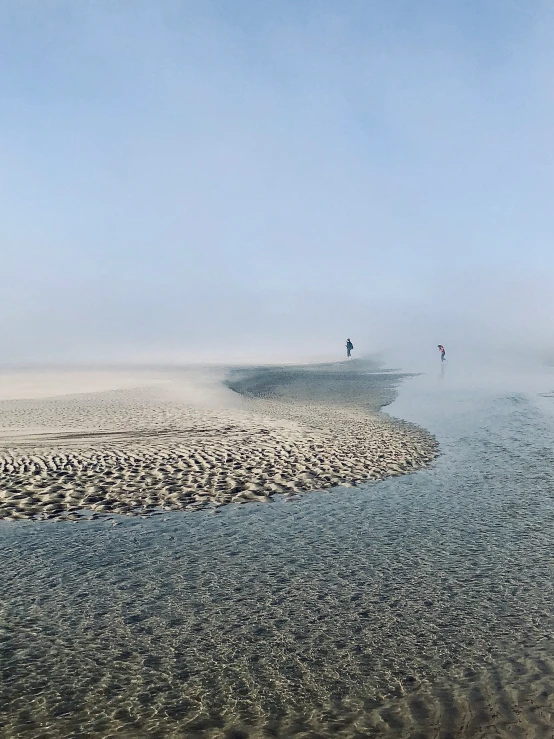 a couple of people are standing at the waters edge