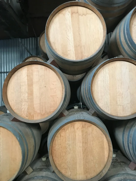 rows of wine barrels stacked up in an aging warehouse