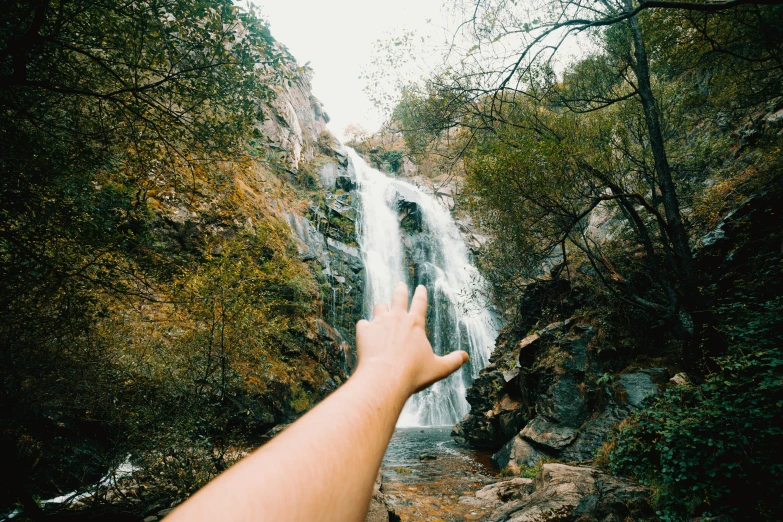 a hand reaching up to the water near some rocks