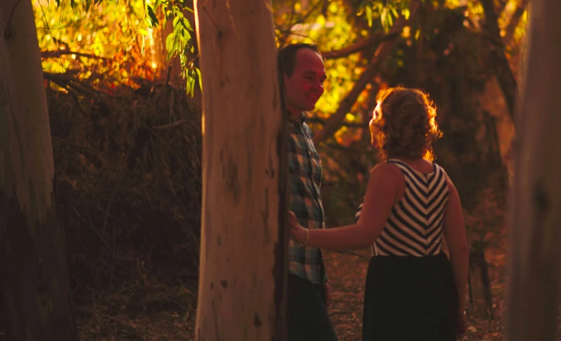 a man and a woman walking through a forest