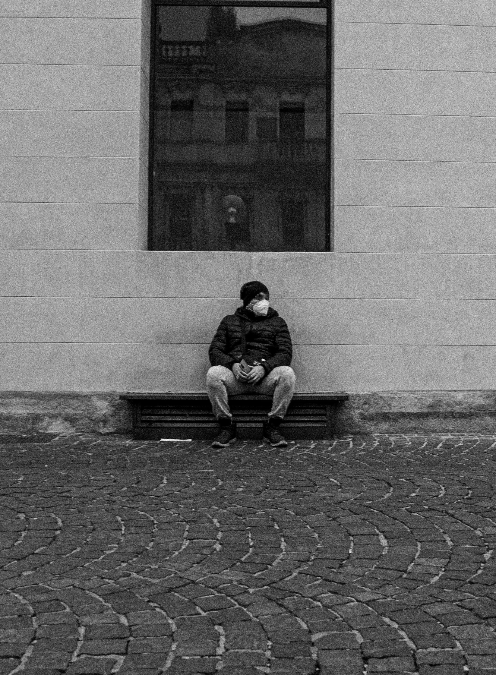 a man sits on a bench and looks out a window