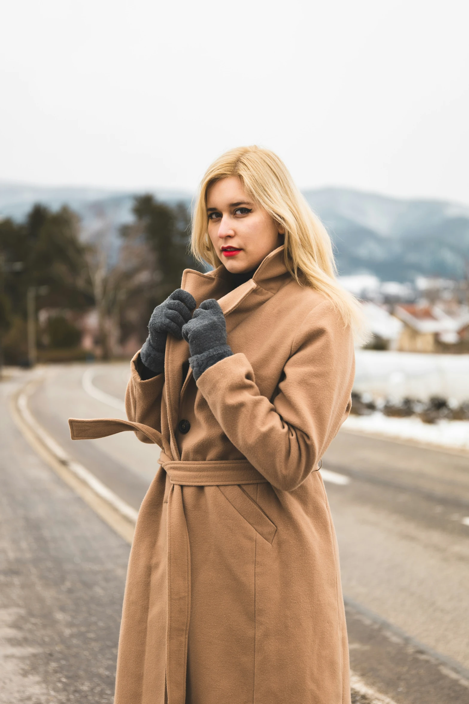 woman in a trench coat standing on a street