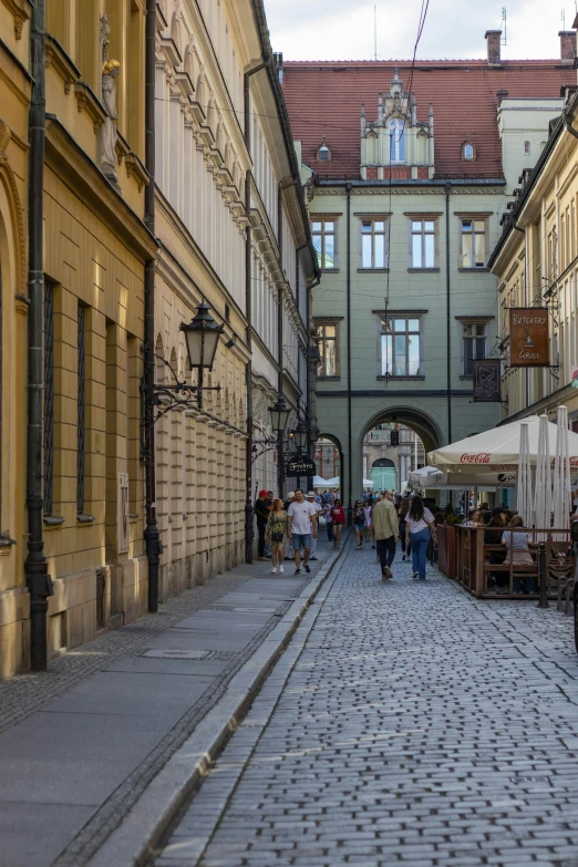 people walking and walking on cobblestone sidewalk in an old city