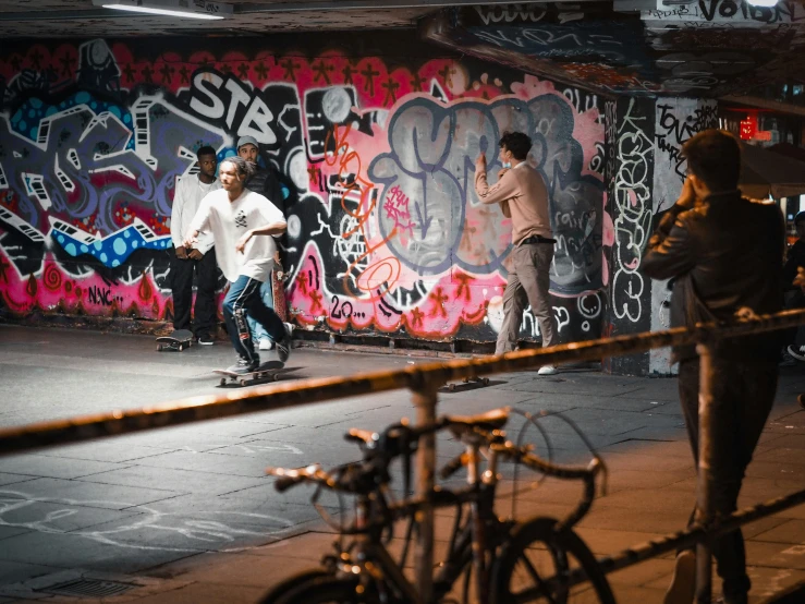 three boys riding their skateboards with graffiti on the wall