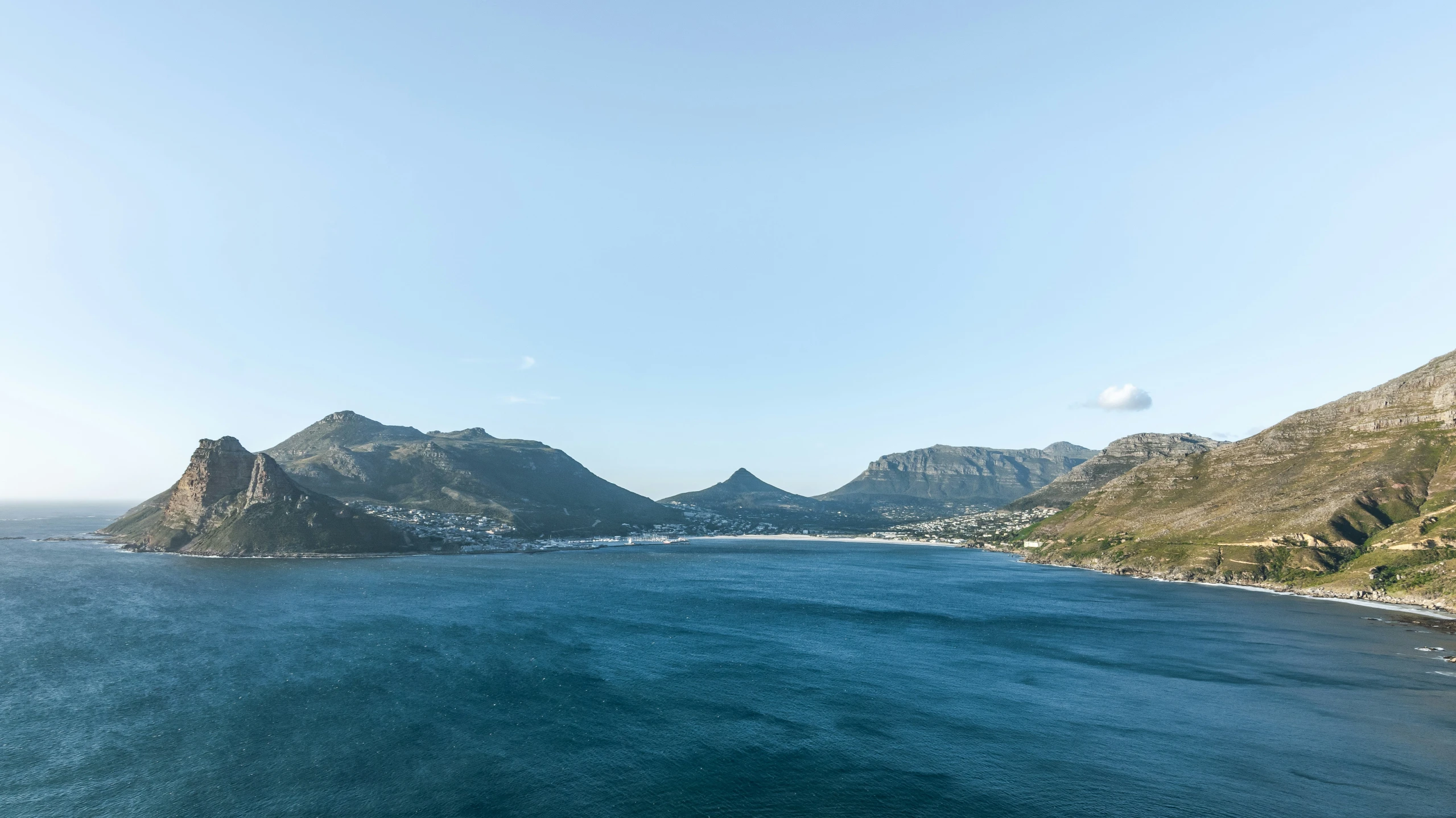 two mountaintops sit in the distance and surrounded by blue water