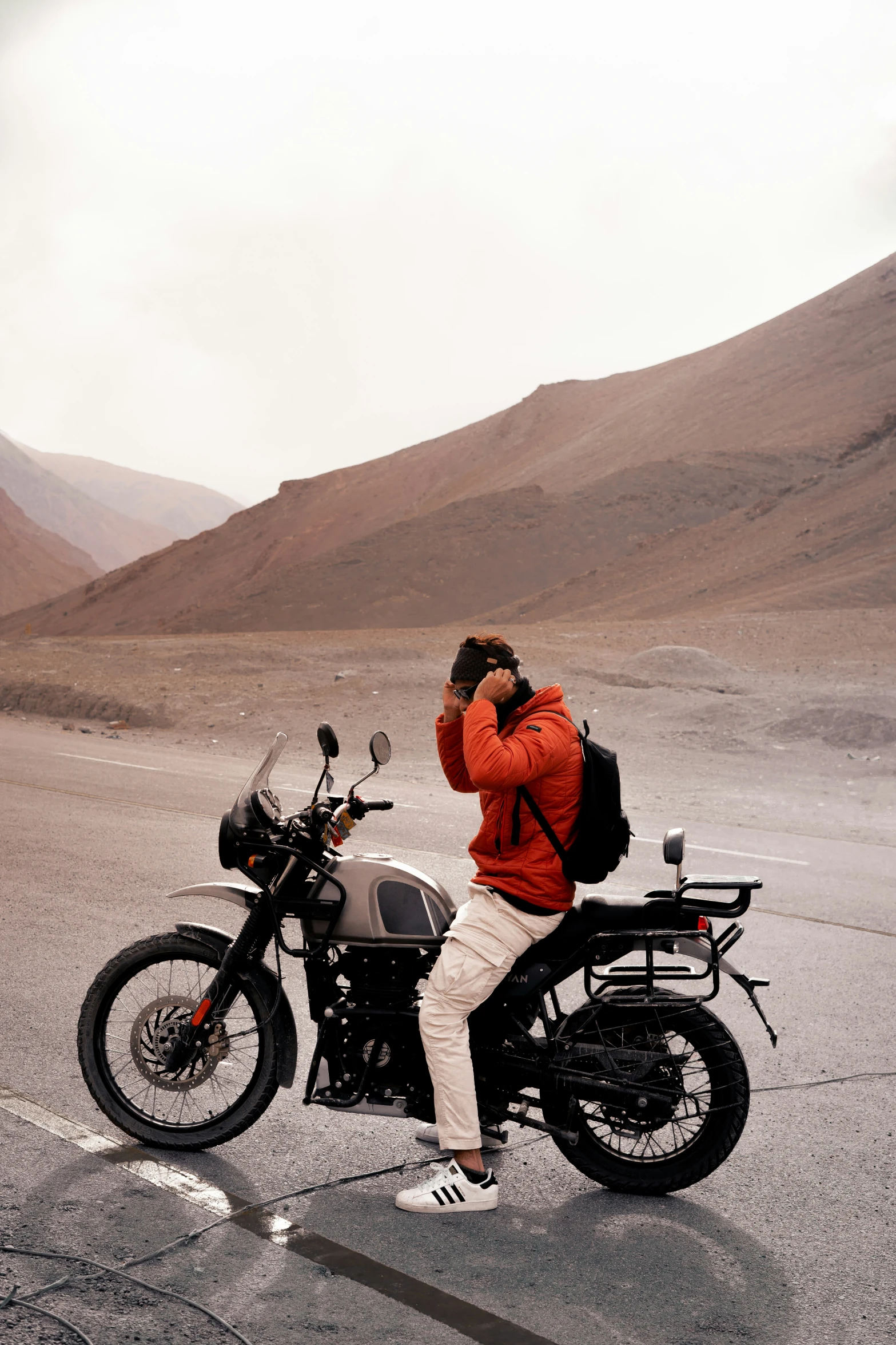 a man in red sweater sitting on motorcycle with cell phone to his ear