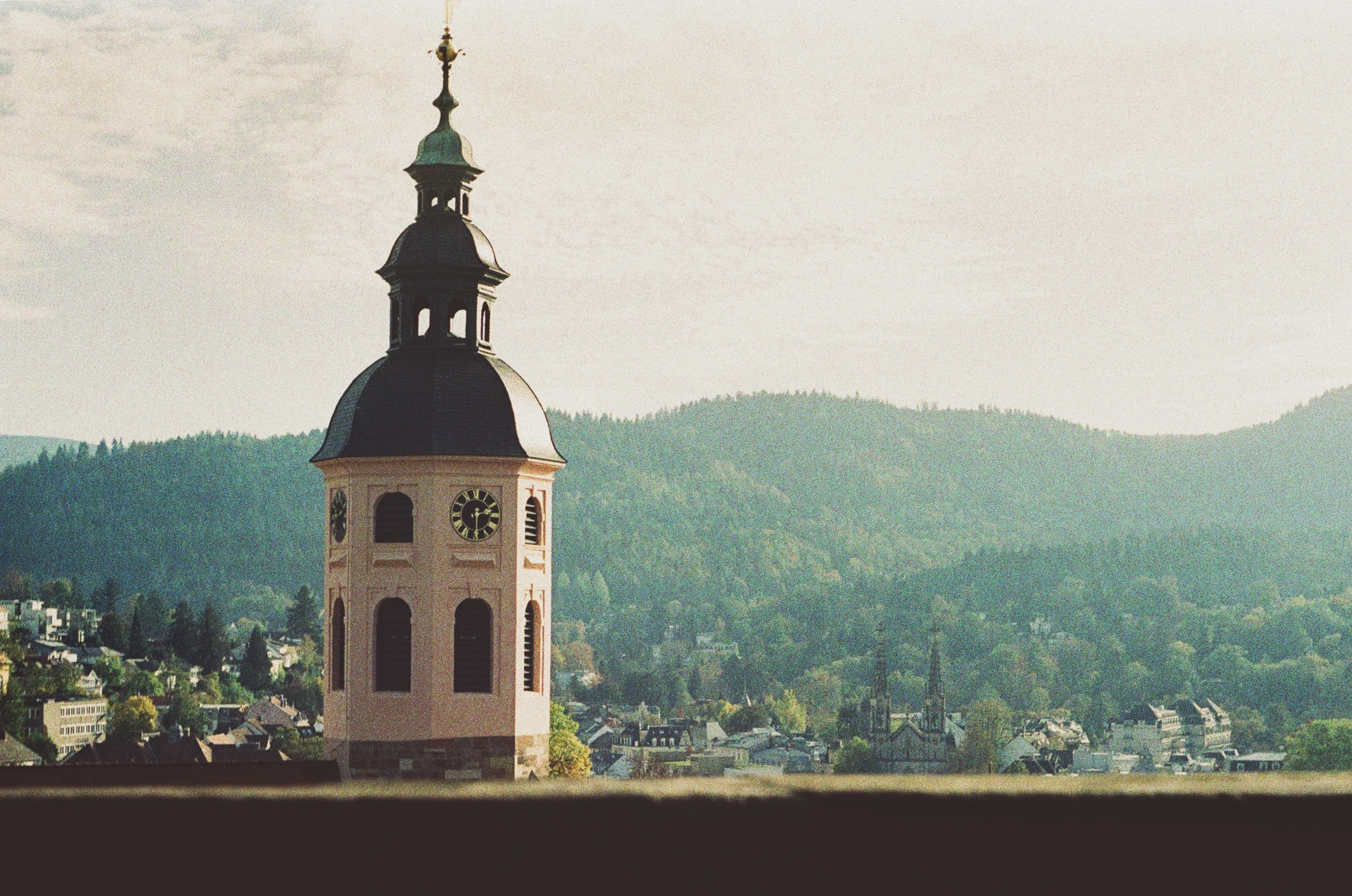 clock tower with mountains in the background and trees