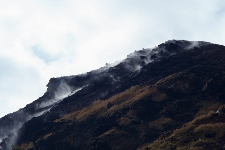 smoke is rising from the top of a rocky mountain