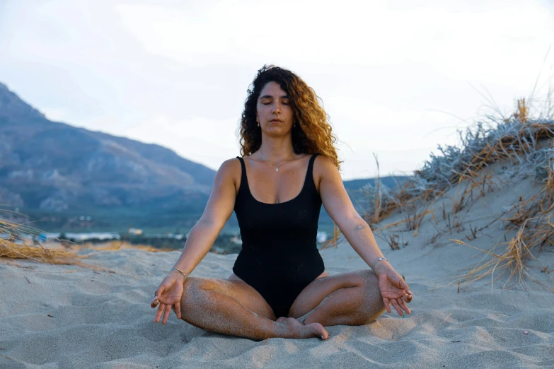 a woman meditating on the beach on a sunny day