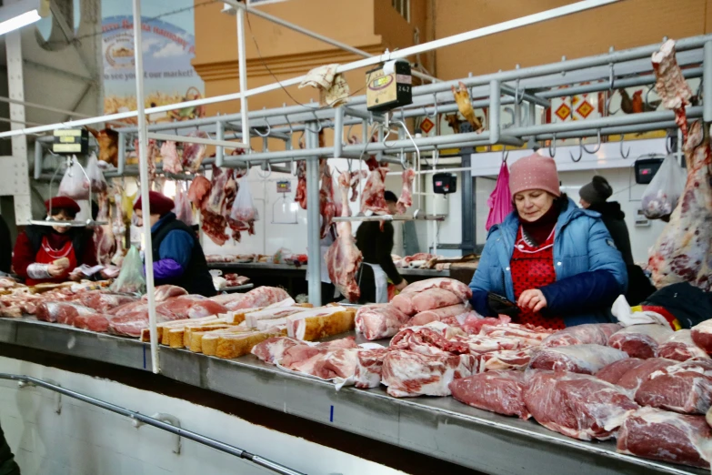 woman preparing meat for sale in large building