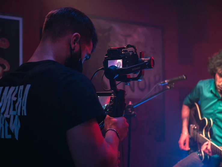 a man playing guitar in front of a camera