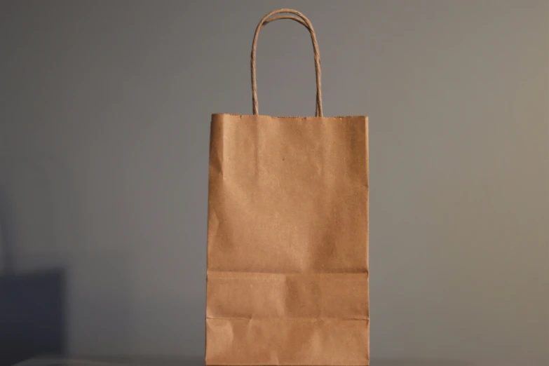 an empty brown shopping bag against a gray wall