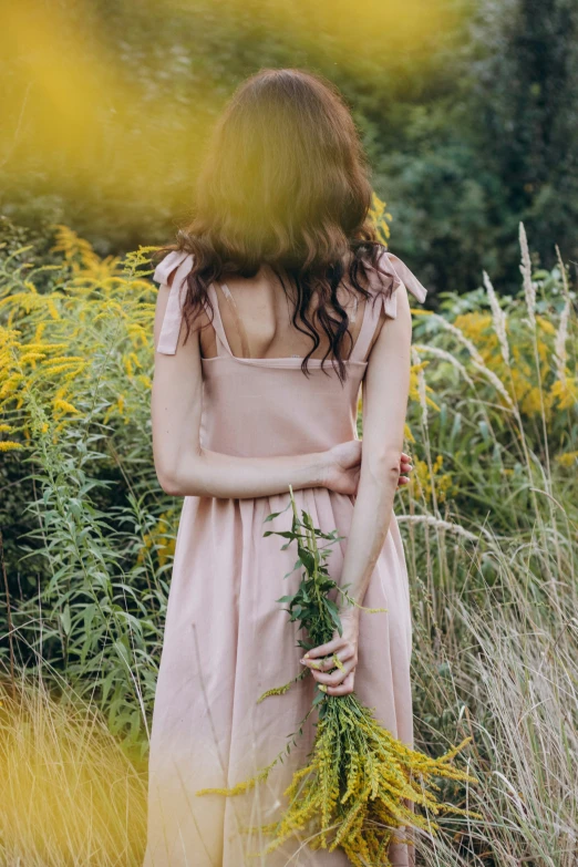 the girl in the dress holds flowers in her hands