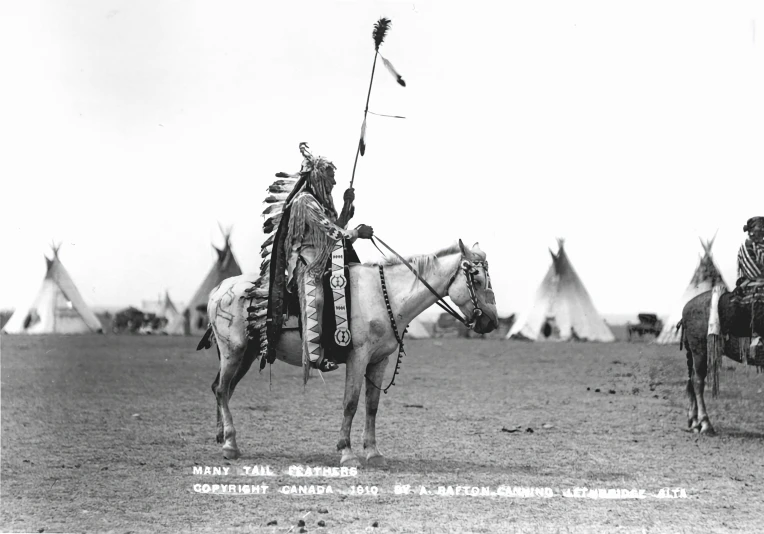 two indian men riding horses in a field